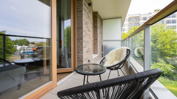 A balcony with a glass door, a small round table, and two chairs.