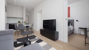 A modern living room with a sofa, a coffee table, a TV, and a dining area with chairs and a table.