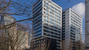 Moderni, korkea kerrostalo, jossa on useita kerroksia, suuret ikkunat sekä lasi- ja betonipintainen julkisivu.
