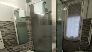 A modern bathroom with a glass-enclosed shower, a white sink, and a toilet.