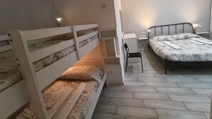 A bedroom with bunk beds, a desk, and a chair.