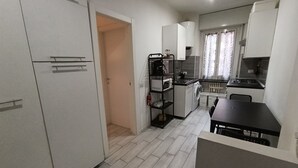 A compact kitchen with white cabinets, a microwave, a stove, and a sink. There's a small dining table with chairs.