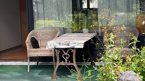 A sunlit patio with wicker furniture, a table, and a stone lion statue. - 2-bedroom flat with own garden (Helsinki)