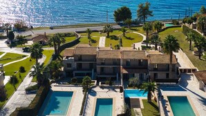 A coastal hotel with multiple swimming pools, a road in the foreground, and a view of the sea and mountains in the background. - Palmrise Luxury Villas - Helios Villa (Kassandra)