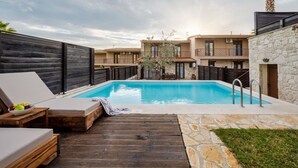 A swimming pool with wooden deck seating and a stone pathway. - Palmrise Luxury Villas - Helios Villa (Kassandra)