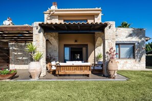 A stone building with a wooden bench and potted plants in front. - Palmrise Luxury Villas - Blue Villa (Kassandra)