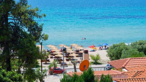 A beach with umbrellas, lounge chairs, and a clear view of the sea.