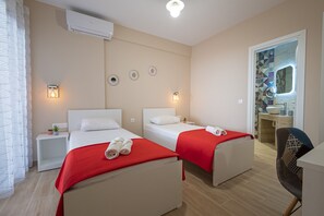Ein Hotelzimmer mit zwei Betten, einem Schreibtisch, einem Stuhl und einem Badezimmer mit Fliesen.