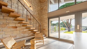 Ein modernes Interieur mit einer Steinwand, einer Holztreppe und Blick durch große Glasüren.