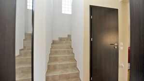 Una escalera con baldosas color beige que lleva a una puerta de madera oscura.