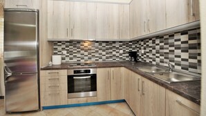Una cocina moderna con armarios de madera, un refrigerador de acero inoxidable, un protector contra salpicaduras a cuadros y un horno empotrado.