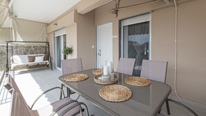 Een eetruimte met een glazen tafel, geweven placemats en comfortabele stoelen.