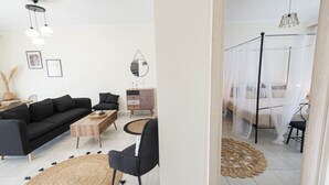 Een moderne woonkamer met een zwarte bank, een houten salontafel en een zwarte fauteuil. Er ligt een rond geweven vloerkleed.