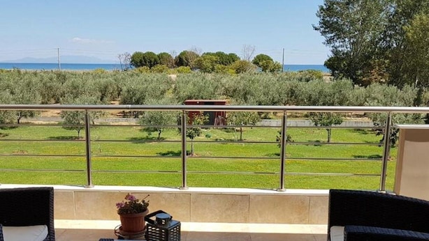 Ein Balkon mit Korbmöbeln, einem Glastisch und einem Blumentopf.