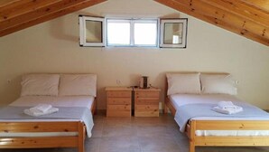 Ein Schlafzimmer mit zwei Holzbett, einem Nachttisch und einem kleinen Fenster mit drei Spiegeln.