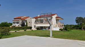 Ein zweistöckiges Wohngebäude mit rotem Ziegeldach, einer überdachten Terrasse und einem Basketballkorb im Vorgarten.