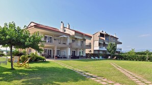 A multi-story residential building with balconies, a well-maintained lawn, and outdoor seating areas. - Villa Iris 1by Rentalspro (Nea Propontida)