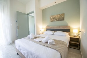 Ein Hotelzimmer mit einem großen Bett, zwei Nachttischen mit Lampen, einer Tür und einem an der Wand befestigten Kunstwerk.