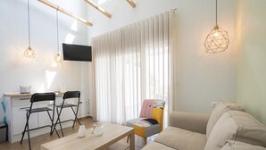 Un salon moderne comprenant un canapé, une table à manger, deux chaises et des luminaires suspendus.