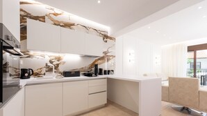 A modern kitchen with white cabinets, a marble backsplash, and a breakfast bar. - Les Maisons Deluxe Superior by Rentalspro (Kassandra)