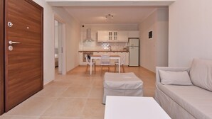 A compact living space with a kitchenette, a dining area, and a sofa. - Fotinia Beach House Ground Floor by Rentalspro (Nea Propontida)