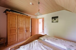 A bedroom with a wooden bed, a wardrobe, and a ceiling fan.