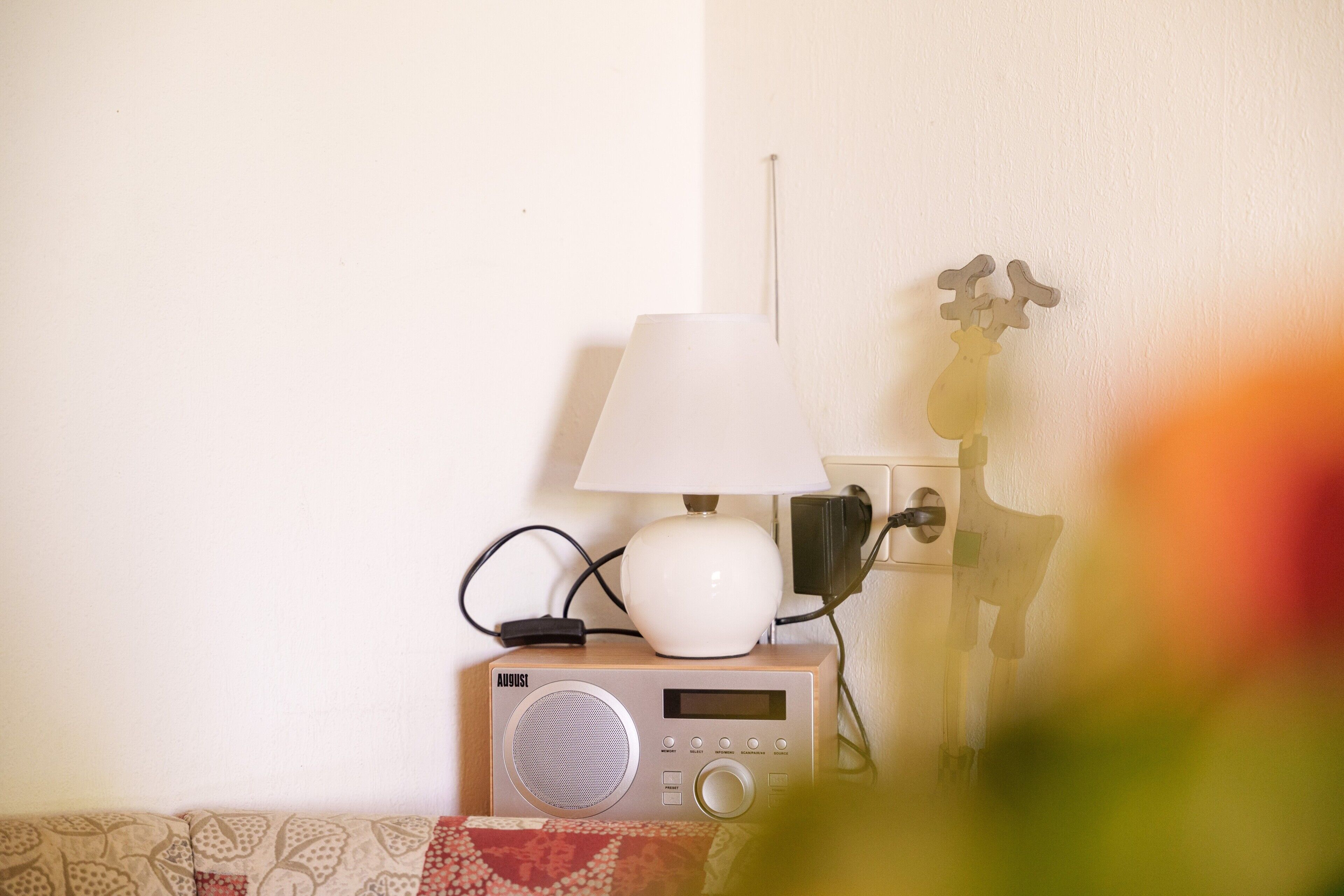 Ein Radio mit einer Lampe obenauf, eine Mehrfachsteckdose und ein an der Wand befestigter Lichtschalter.