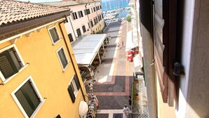 A narrow street with buildings on either side, a clear sky, and a view of the sea in the distance.