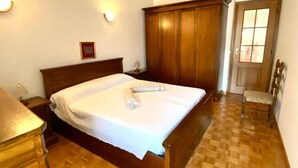 A bedroom with a wooden bed, a nightstand, a wardrobe, and a chair.