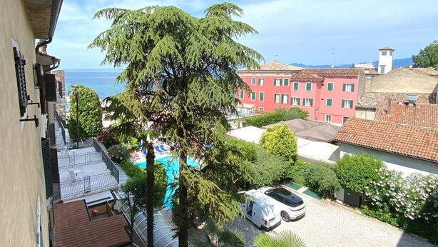 A residential area with a swimming pool, parked cars, and a view of the sea.