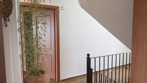 A staircase with a wooden handrail and a metal railing, leading to a room with a large potted plant. - Casa Natura Rodanthi by Rentals Pro (Nea Propontida)