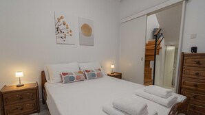 A neatly arranged bedroom with a bed, two bedside tables with lamps, a wooden dresser, and a mirror.