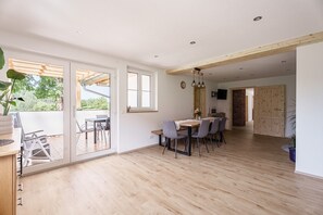 Un comedor amplio con mesa y sillas de madera, ventanas grandes y vistas a zonas verdes.