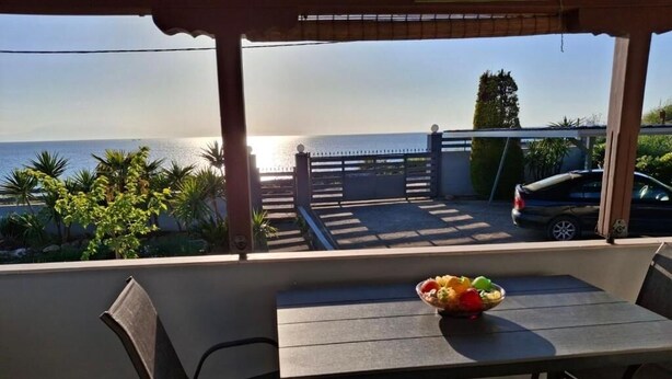 Ein Balkon mit Tisch und Stühlen, einer Obstschale und Blick aufs Meer.