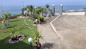 Ein angelegter Garten mit einem Pfad zu einem Tor, mit Blick auf einen Strand.