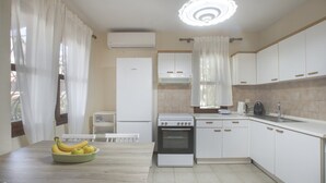A kitchen with white cabinets, a Bosch refrigerator, a stove, and a dining table with chairs. - Eria Home by Rentalspro - Trikorfo Halkidiki (Polygyros)