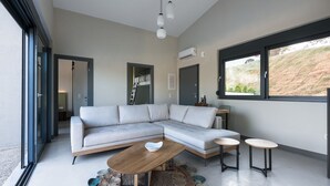 A modern living room with a sectional sofa, a wooden coffee table, and two side tables. - Theeta Elia Villa - Metamorfosi Halkidiki (Sithonia)
