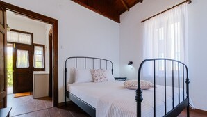 Un dormitorio con estructura metálica en la cama, una mesita de noche y una lámpara.