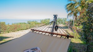 A hammock under a canopy with a magazine, overlooking a garden and a view of the sea. - Eternal Blue by Rentalspro-hanioti Halkidiki (Kassandra)