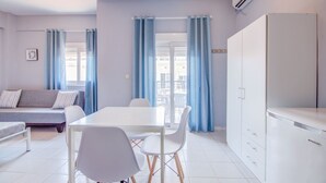 Un salon moderne comprenant un canapé, une table à manger avec des chaises et un coin cuisine avec des placards et un appareil de climatisation.