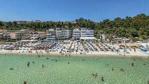 A beach with clear water, umbrellas, and people. - Poseidon Edge No5 by Rentalspro - Kallithea (Kassandra)