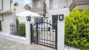 A modern two-story building with a gated entrance, stone steps, and a small patio area. - Violeta Apartment by Rentalspro (Nea Propontida)