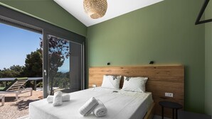 A modern bedroom with a large bed, wooden headboard, and a view of the outdoors. - Theeta Pefko Villa - Metamorfosi Halkidiki (Sithonia)
