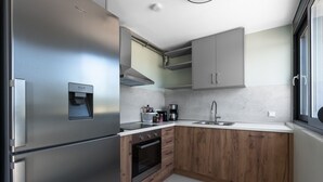 A modern kitchen with stainless steel appliances, wooden cabinets, and a built-in oven. - Theeta Pefko Villa - Metamorfosi Halkidiki (Sithonia)