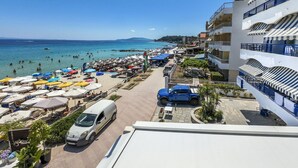 A beachside hotel with a view of the sea, outdoor seating, and a parking area.