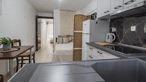 A modern kitchen with a marble backsplash, white cabinets, and a built-in oven. - Tommy Seafront No 1 by Rentalspro - Nea Flogita (Nea Propontida)