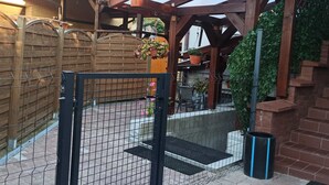 Un patio clos, agrémenté d’une pergola en bois, de plantes en pot et d’un mur en briques.