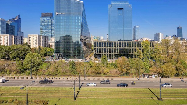 A cityscape with modern skyscrapers, a parking lot, and a clear sky.