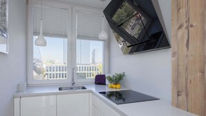 A modern kitchen with a window, white cabinets, a black induction cooktop, and a purple toaster.