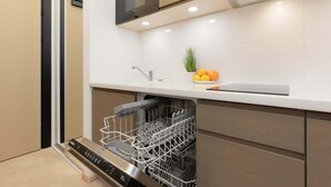 Une cuisine moderne équipée d’un lave-vaisselle, d’un évier et d’un plan de travail agrémenté d’une plante et de fruits.